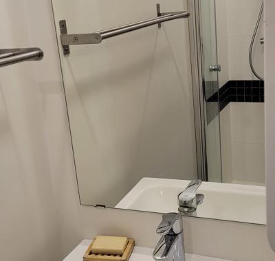 Chambre à louer avec salle de douche, évier et petit-déjeuner.